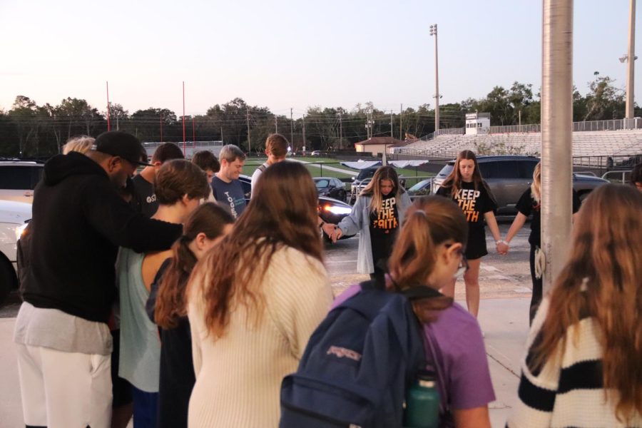 The Fellowship of Christian Athletes are up early; hand-in-hand gathering around the flag pole for their annual prayer. 