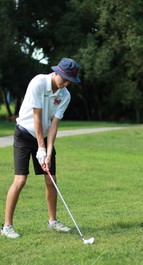 Senior Hayden Kinder puts the golf ball towards a hole.