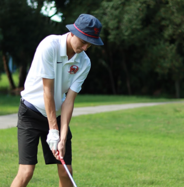 Senior Hayden Kinder puts the golf ball towards a hole.