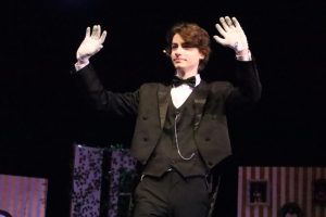 Sophomore Ashe Herod puts his hands in the air, highlighting his role in the performance of Clue.