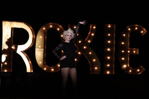 Victoria McGrogan stands illuminated in front of Roxie's sign.