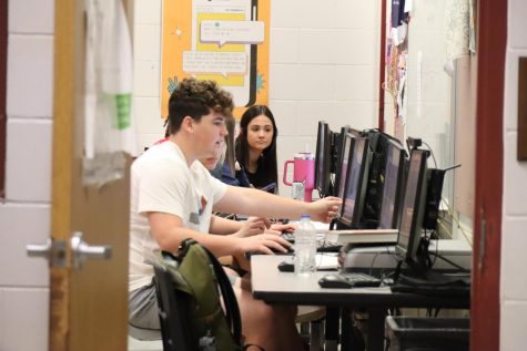 Sophomore Micah Thorpe works on a yearbook spread with the help of his editor. Photo by Maddy Baczek.