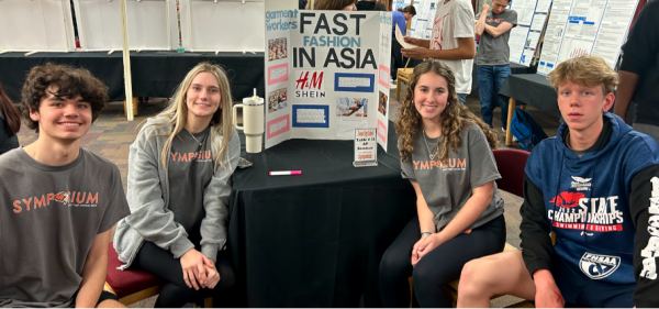 Juniors Nelson Kanistras, Lindsey Miller, Allison Poquette, and Jeremiah Goodwin pose next to their AP Seminar project, titled Fast fashion in Asia. 