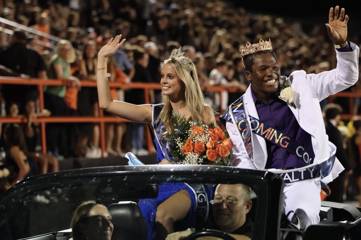  Laureli Herrera and Isaiah Guthrie-Stringer paraded around the track from the backseat of a convertible. Crowns sparkling, the drum major and the cheerleader waved out to the crowd. 
