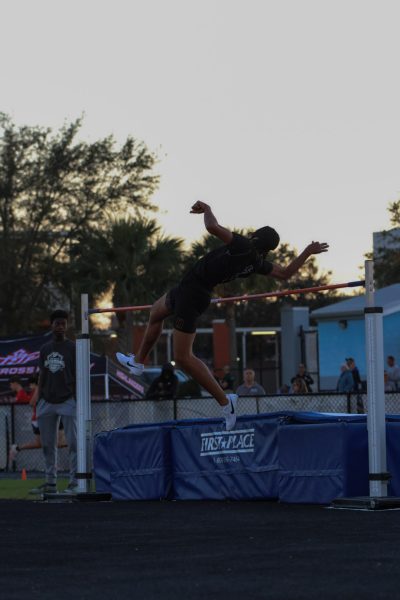 Junior Aiden Demeglio leaping over the bar in the high jump. Demeglio arches his back to clear in narrow margins.