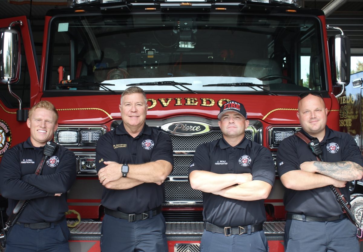 Firefighters Eric Long, Matthew Rothfuss, Josh Wolf, and Jeff Pirkola pose for a picture in front of the station's brand new firetruck, arms crossed.