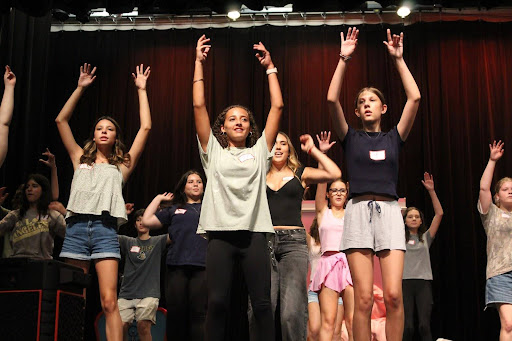 Students raise their hands high to show off their skills to the casting directors at "Grease" auditions.