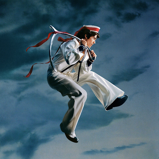 Conan Gray leaps in the air adorned with sailor attire and a wishbone in hand, fitting for the album title.