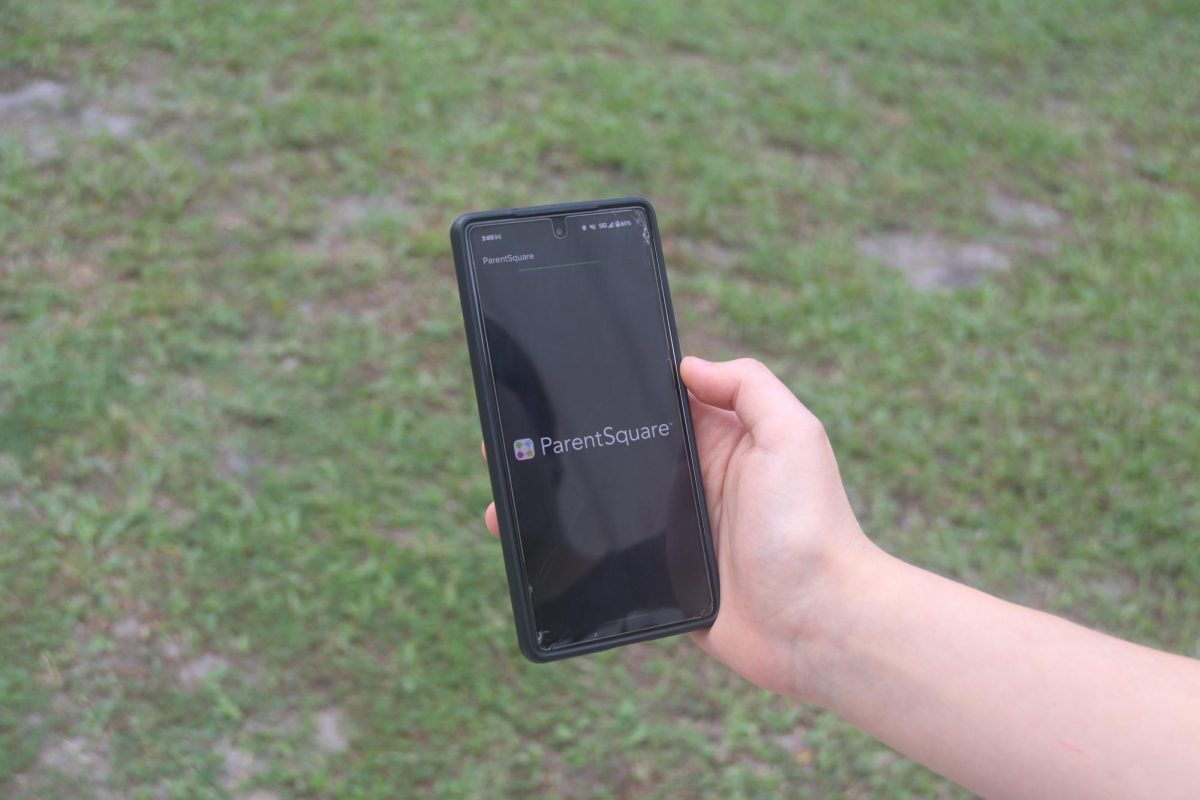 A student holds their phone while opening the ParentSquare app.