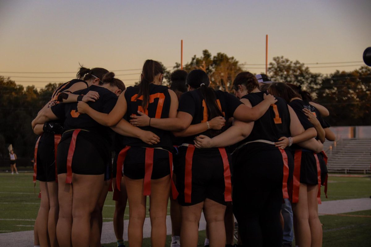 The junior powder puff players circle in a huddle to pump up and motivate their team for the win.
