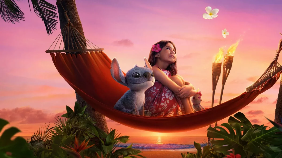 In "Lilo & Stitch" (2025), blue alien Stitch sits with Lilo (Maia Kealoha) on a hammock. Image courtesy of Walt Disney Studios Motion Pictures.