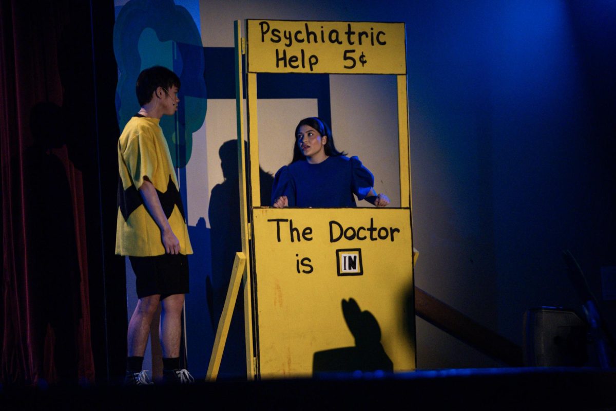 At her Psychiatric Help stand, Lucy van Pelt (Emma Bremer, 12) gives Charlie Brown (Aiden Tesinsky, 12) advice for the low cost of five cents.