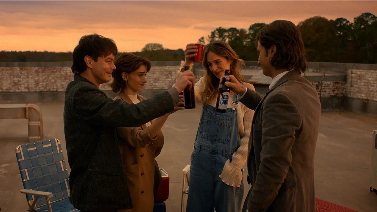 Jonathan (Charlie Heaton), Nancy (Natalia Dyer), Robin (Maya Hawke) and Steve (Joe Keery) raising their drinks up in a bittersweet gathering months after the final battle against Vecna. Image courtesy of Netflix.