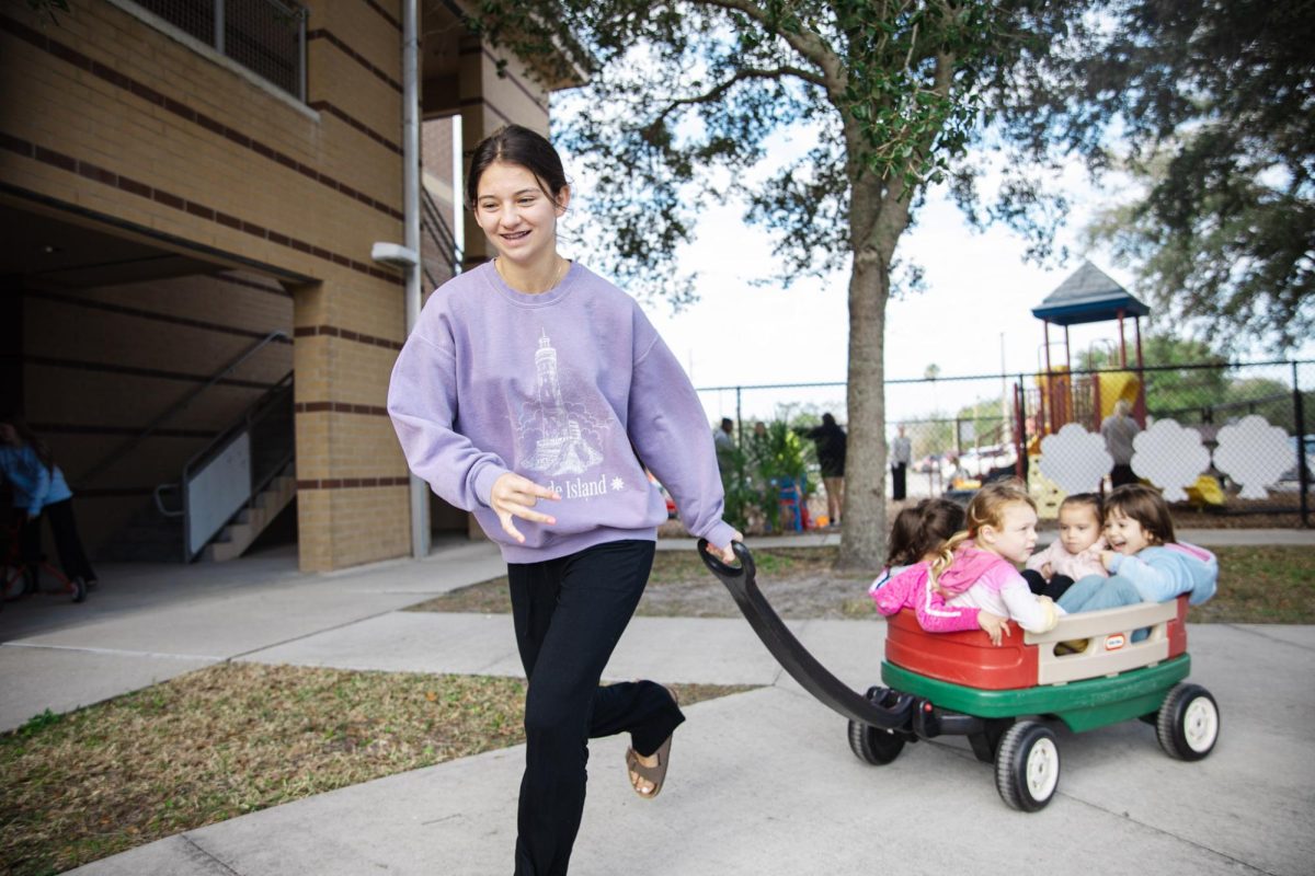 Sophomore Alyssa Griffin hauls a toy wagon with four preschool girls along for the ride inside.