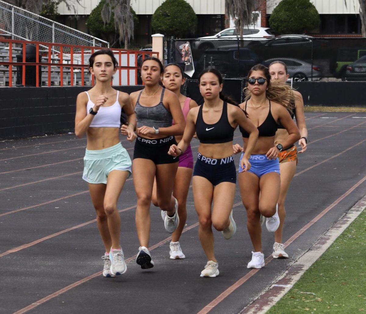 At their practice on Feb. 18, a group of girls track and field runners jog on the track.