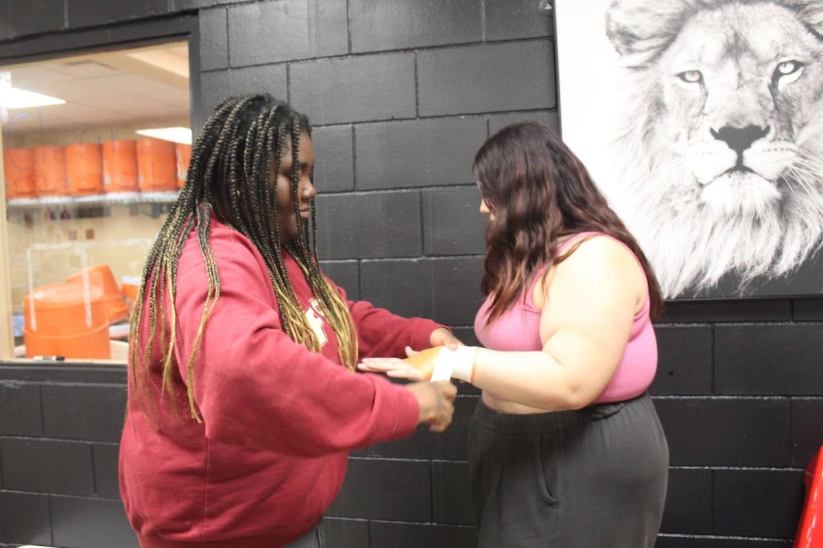 Cody Moise practices her wrapping skills on her fellow trainer Olivia Rodriguez. 