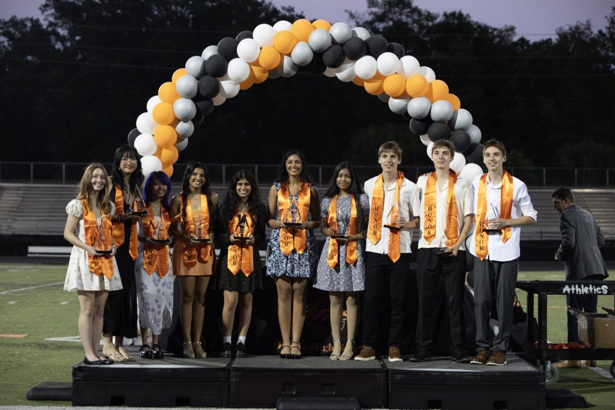 The Top Ten-ranked seniors smile for a photo, holding their trophies which they earned through four years of rigorous courses and high grades. Left to right: Elise Elwell, Jade Wang, Sofia Ascue, Mannat Bakshi, Anya Boga, Gargi Paranjape, salutatorian Moitri Santra, valedictorians Colin Aysun, Brody Aysun, and Aiden Aysun.