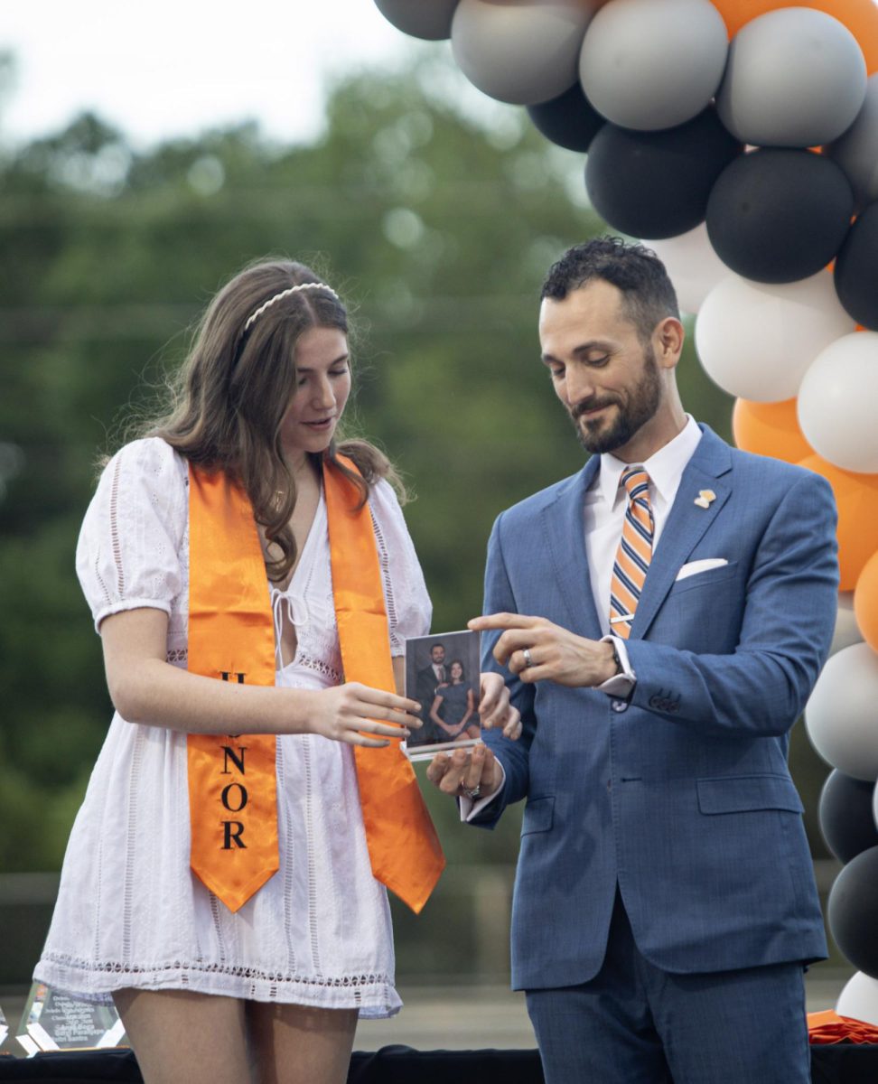 Looking down at their portrait, Trinity Gillispie smiles with her sponsor William Furiosi.